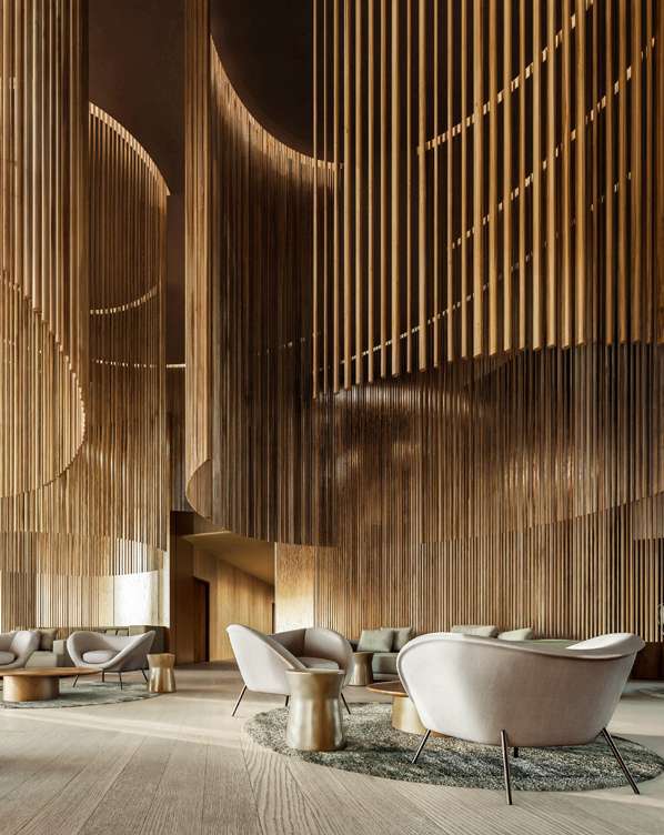 Lounge chairs gathered beneath tall curving walls of timber rods