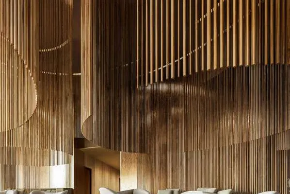 Lounge chairs gathered beneath tall curving walls of timber rods